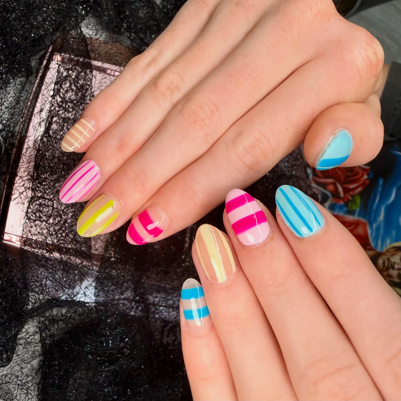 Nails striped in pink, yellow, lime and blue, a different pattern on each one
